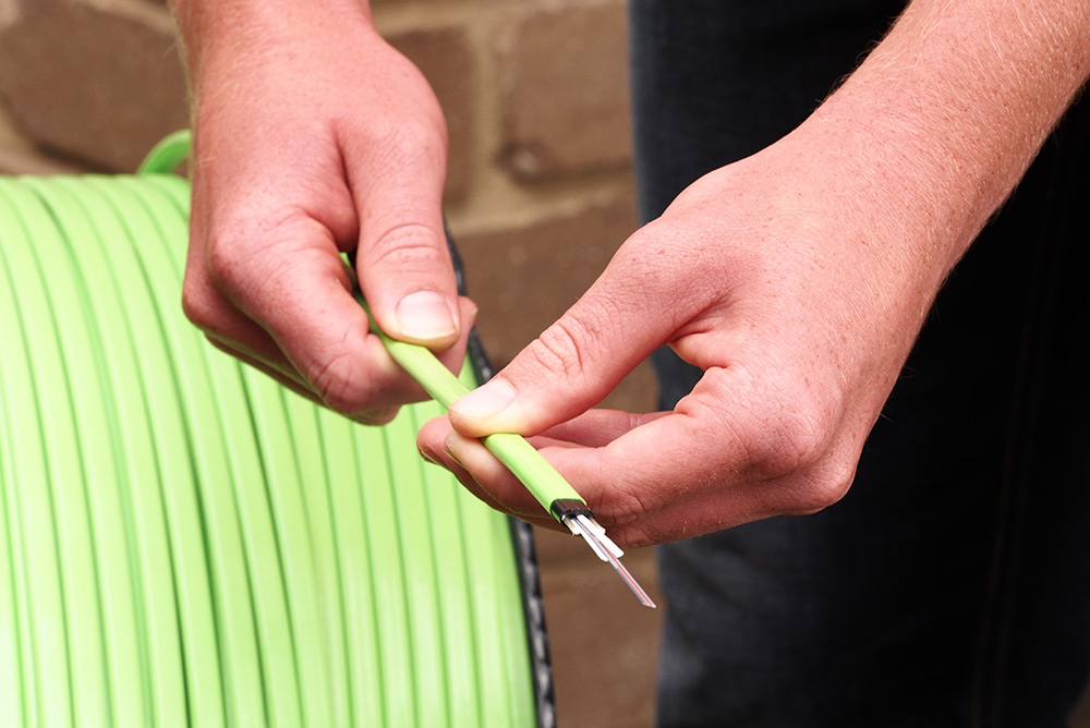 Close up of fibre optic specialist holding exposed data cable