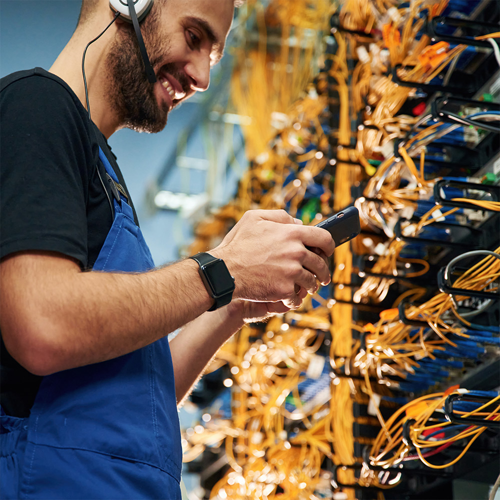 Smiling fibre optic engineer repairing data centre cables